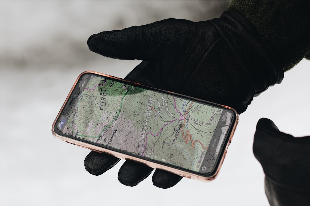 A hand holds a smartphone displaying a map with glowing points and connection lines, representing hyper-local digital marketing networks.