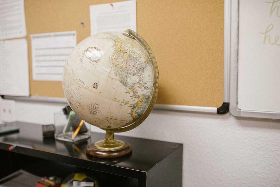 A small globe and a detailed city map side-by-side on a clean desk, visually comparing the concepts of global reach versus local targeting.