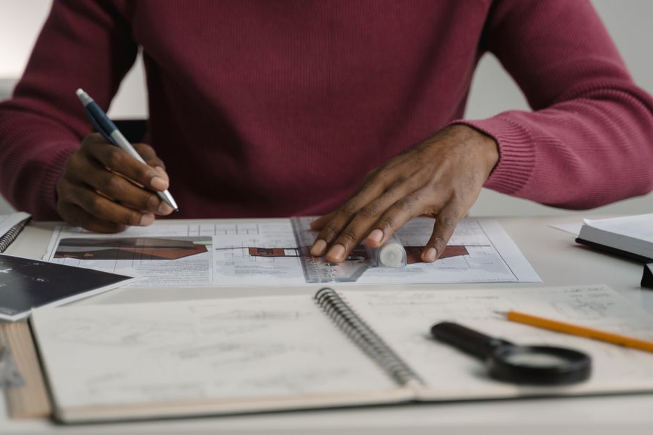 A close-up of a real estate professional's hands carefully drafting a blueprint, representing expertise and building a brand from the ground up.